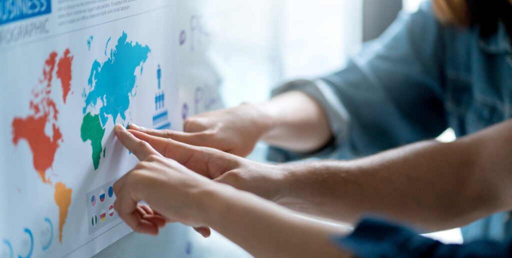 Business team discussing international strategy with a world map, planning global expansion and market targeting.