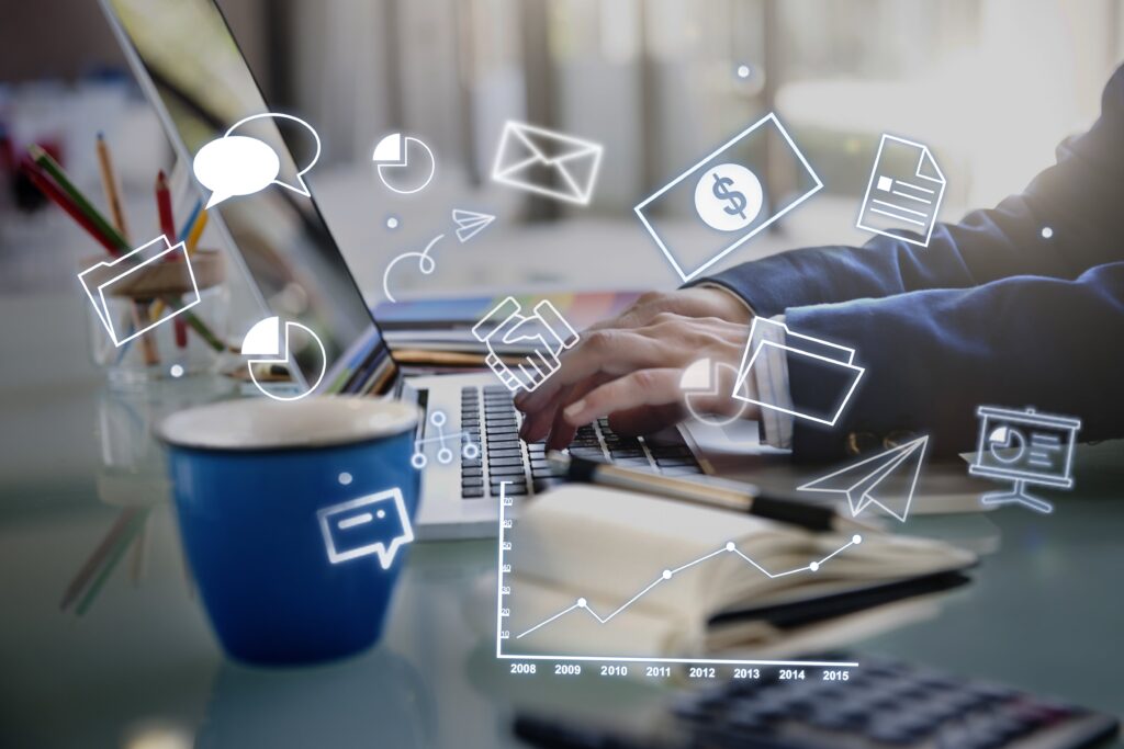 Business professional typing on laptop with digital marketing icons and analytics overlay, representing data-driven strategy and online branding solutions.